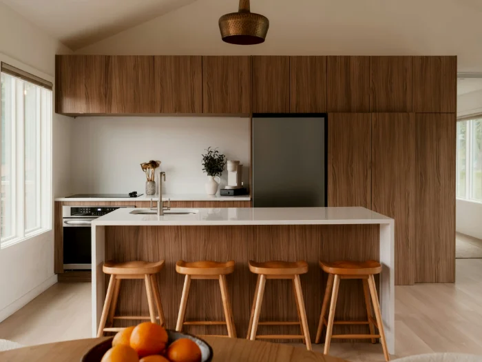 Walnut kitchen with a white island and four wooden stools under a copper pendant