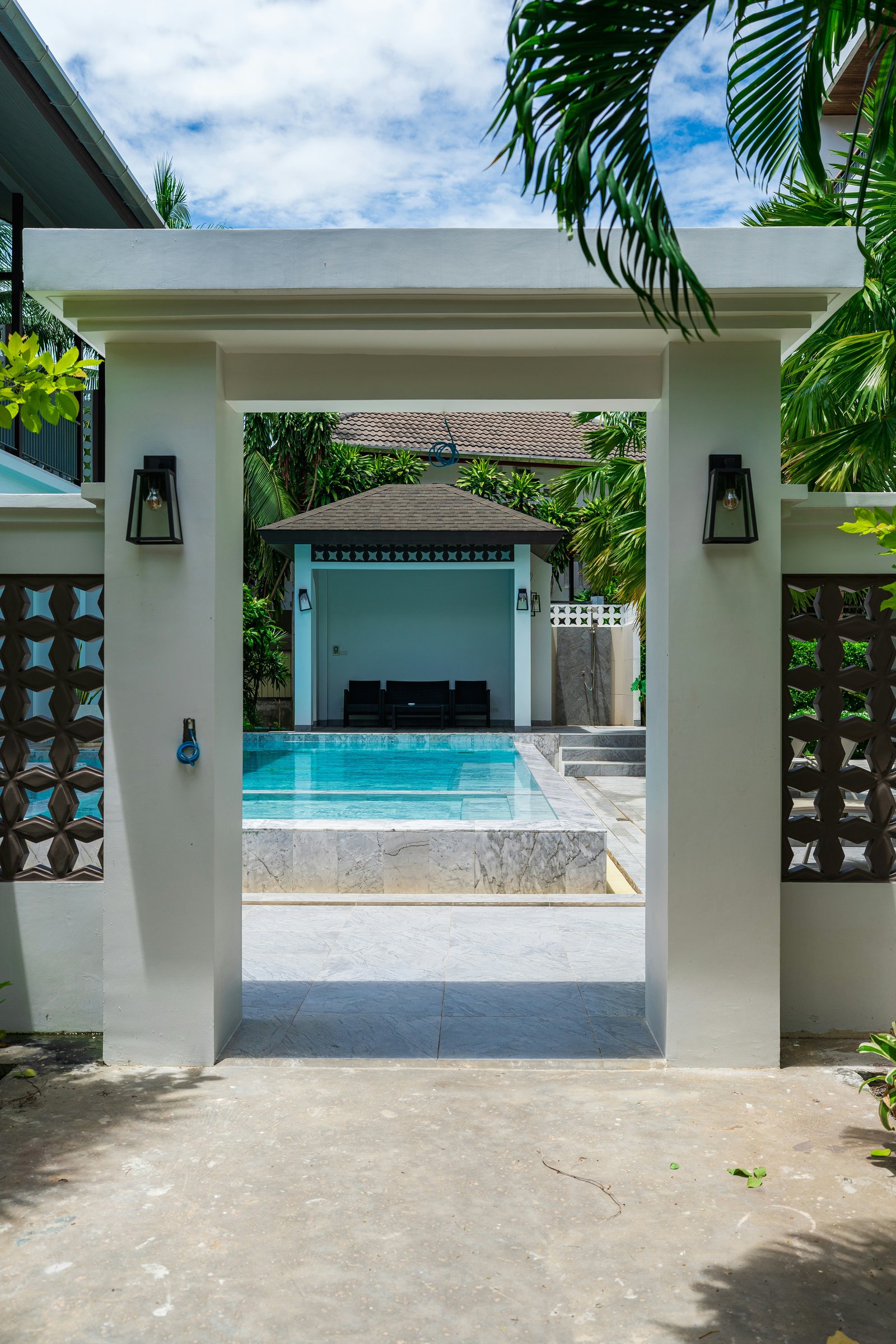 A contemporary resort walkway framed by palms and opening onto a pool courtyard