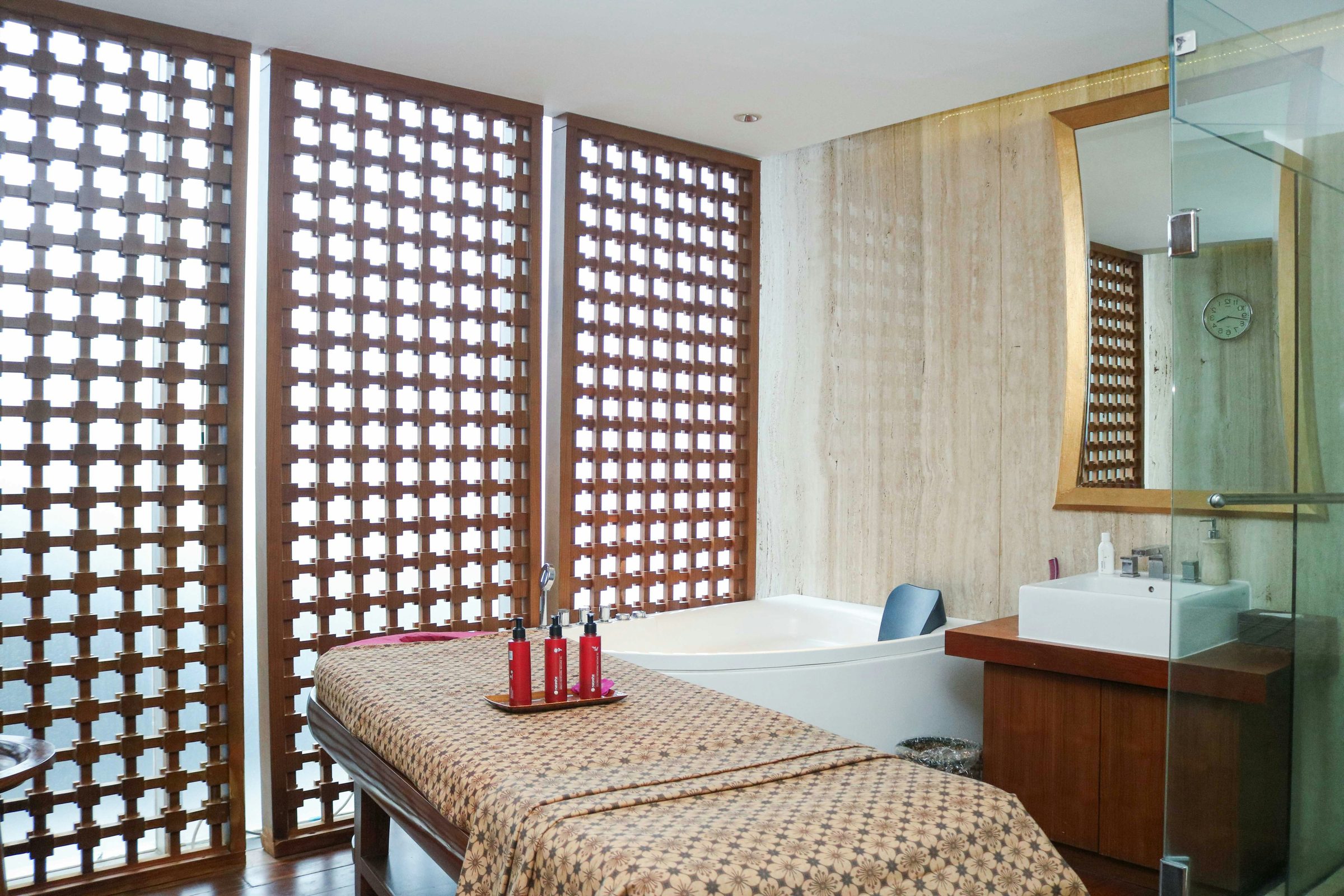 An empty contemporary treatment room with a massage table and glass shower