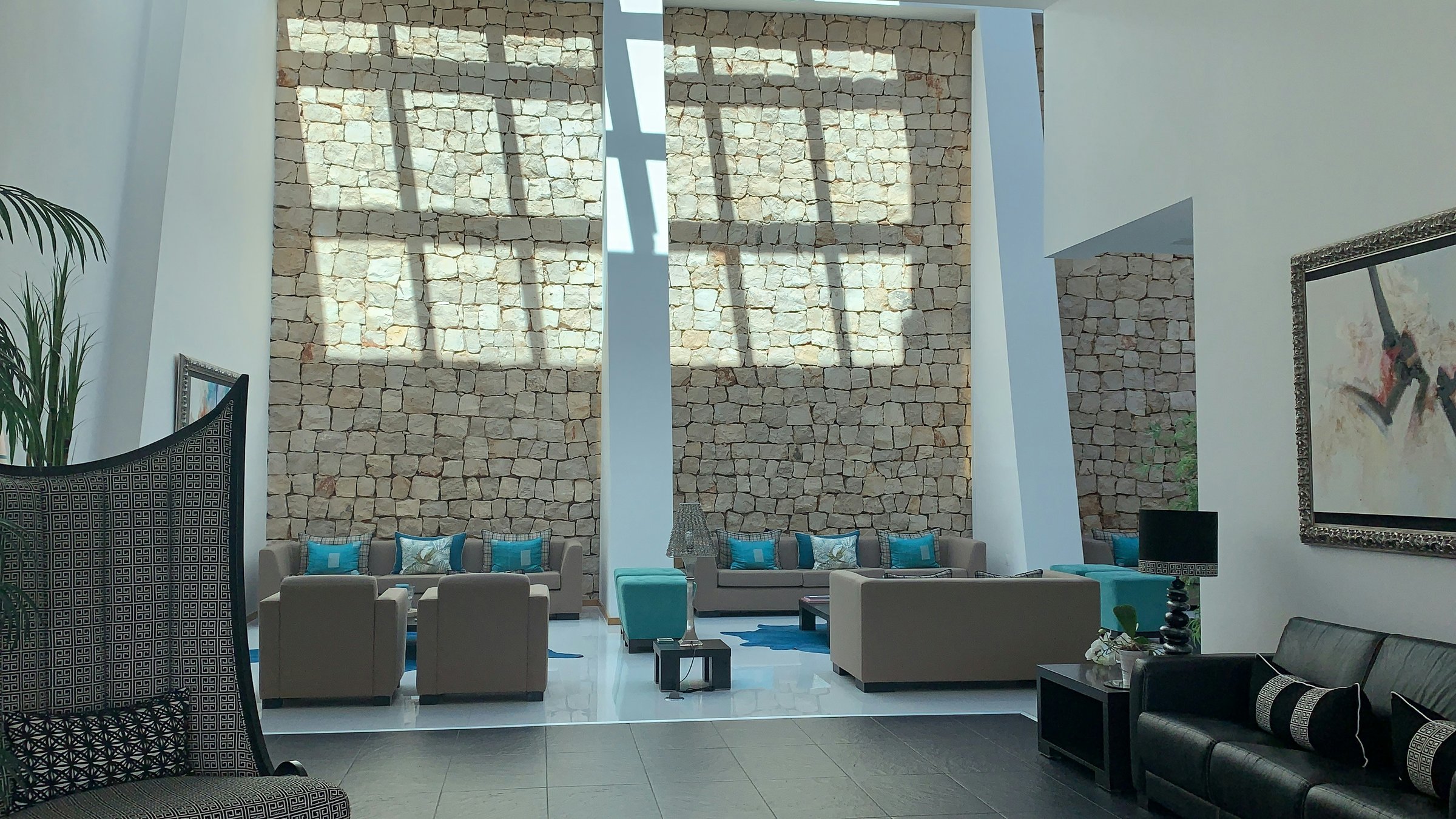 Contemporary hotel furniture, framed artwork and a sunlit natural stone wall