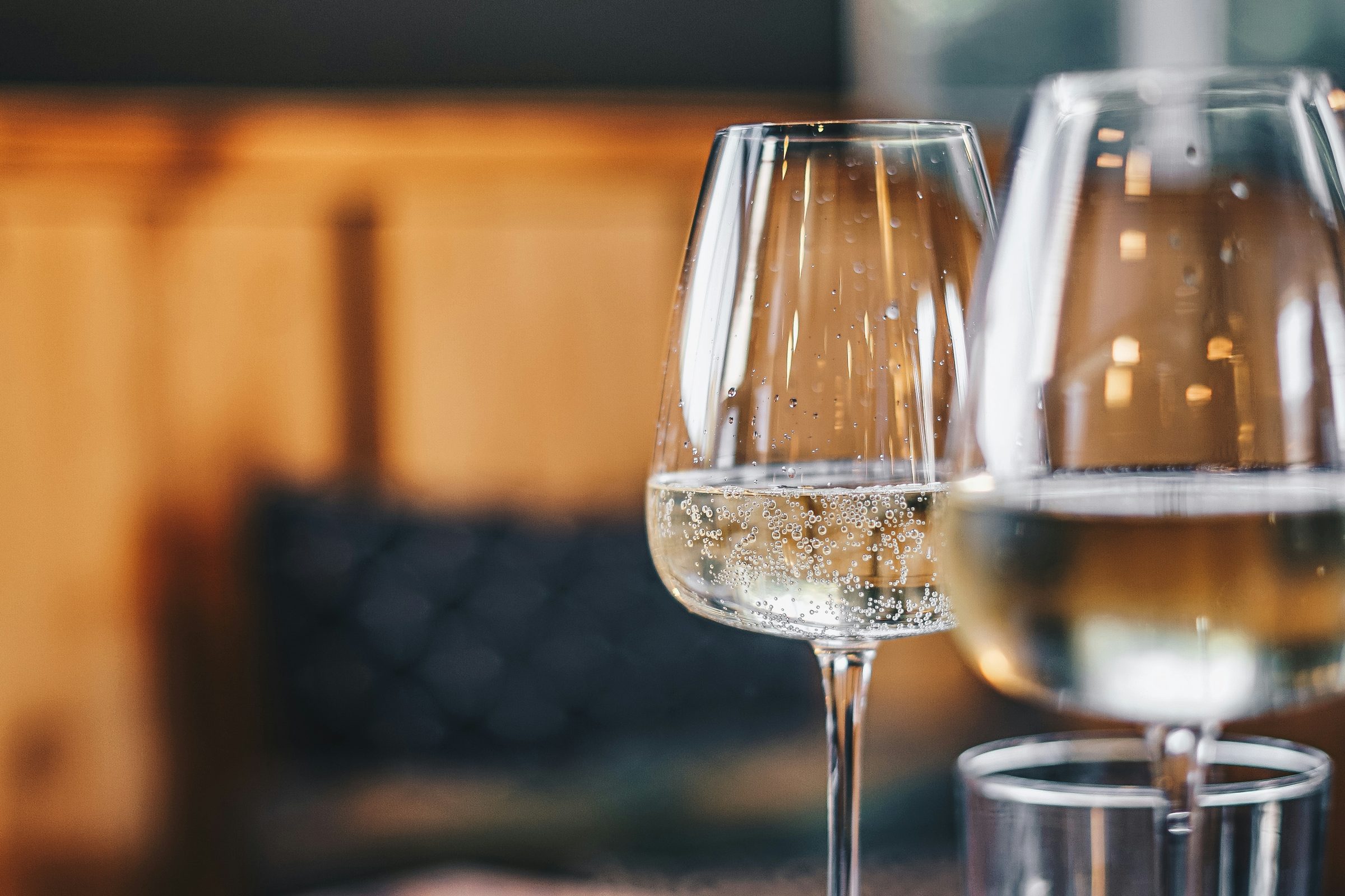 Wine glasses on a sunlit restaurant table with timber seating